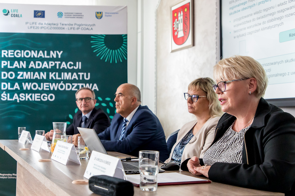 Panel dyskusyjny podczas briefingu prasowego w Krzepicach o Regionalnym Planie Adaptacji do zmian klimatu dla Województwa Śląskiego, przy stole siedzi czworo prelegentów.