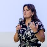 Agnieszka Fitrzyk – kierowniczka referatu ds. planowania w zakresie środowiska w Departamencie Ochrony Środowiska, Ekologii i Opłat Środowiskowych Urzędu Marszałkowskiego Województwa Śląskiego prowadzi prelekcję trzymając mikrofon, w tle jasny ekran prezentacyjny