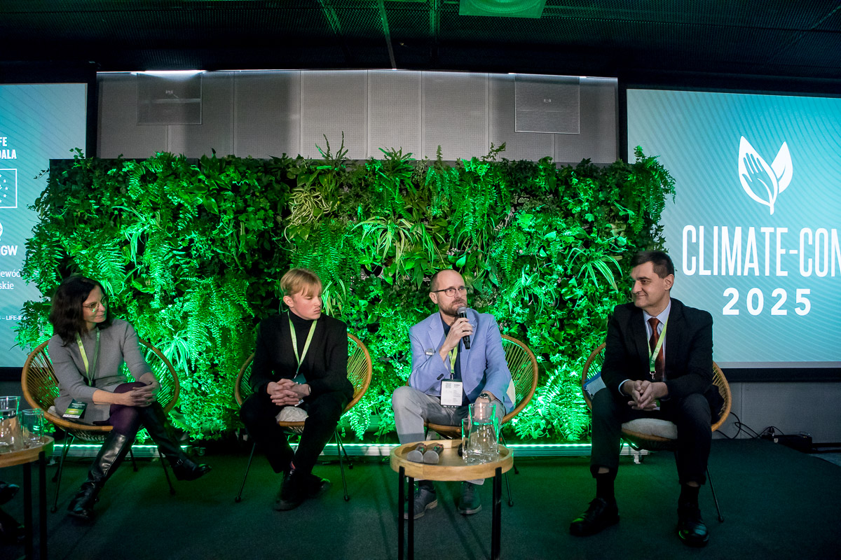 Panel dyskusyjny z czterema osobami na scenie, w tle zielona ściana roślinna i napis „Climate-Con 2025"