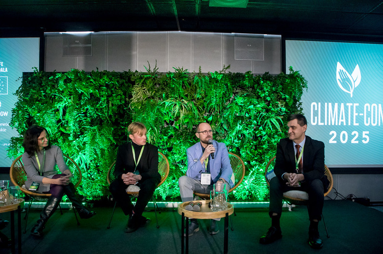 Panel dyskusyjny z czterema osobami na scenie, w tle zielona ściana roślinna i napis „Climate-Con 2025"