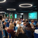 Widok sali konferencyjnej z uczestnikami siedzącymi w rzędach, na ekranie logo „Climate-Con 2025