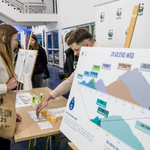 Stoisko edukacyjne WWF z planszą „Zasolenie wód”, uczestnicy oglądają wykres i rozmawiają
