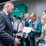 Osoba wręcza dyplom grupie uczestników stojących na scenie przed planszą „Climate-Con”