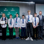 Grupa uczestników z nagrodami i certyfikatem pozuje na scenie przed planszą „Climate-Con”